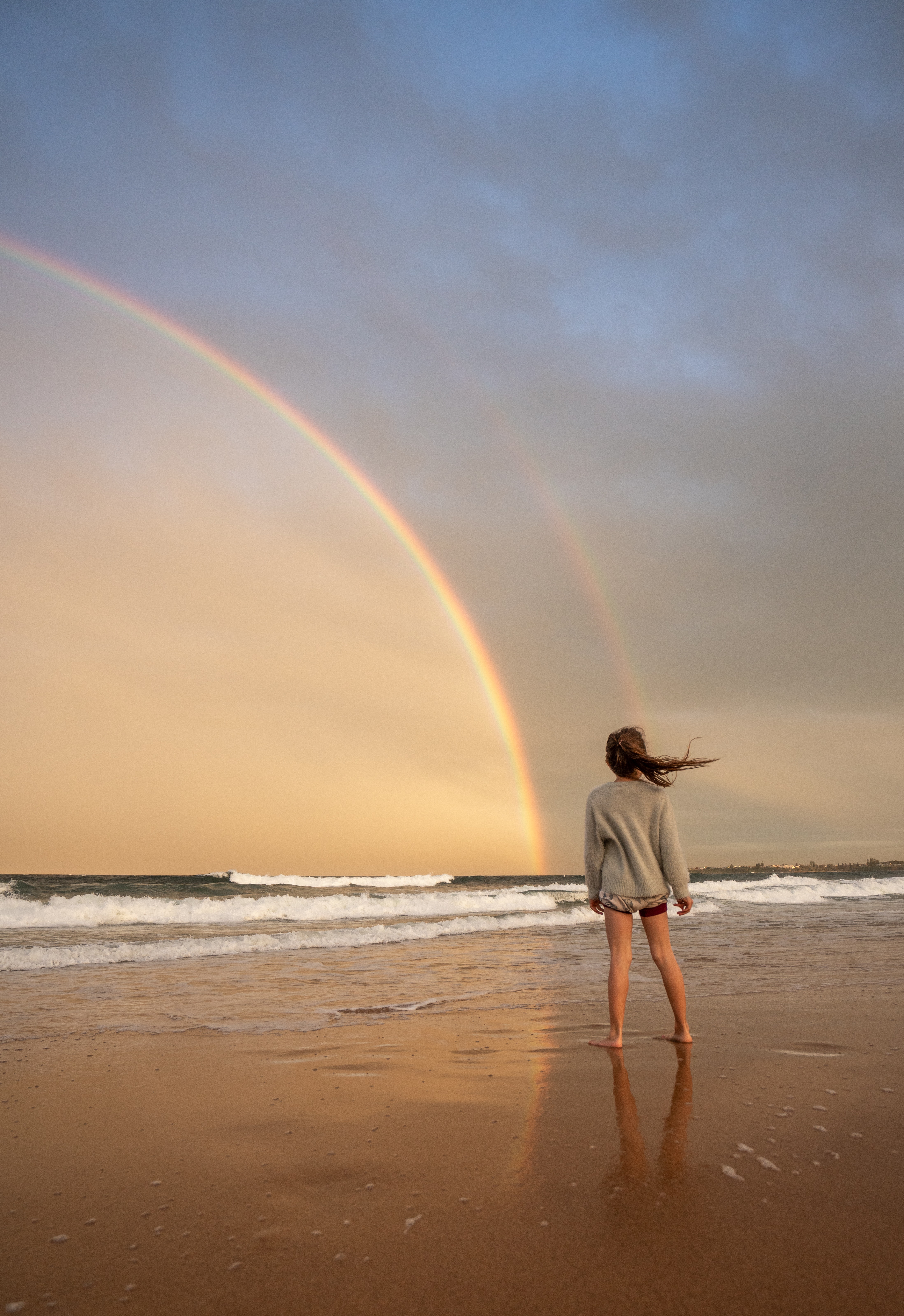 woman on the beach viewing a rainbow